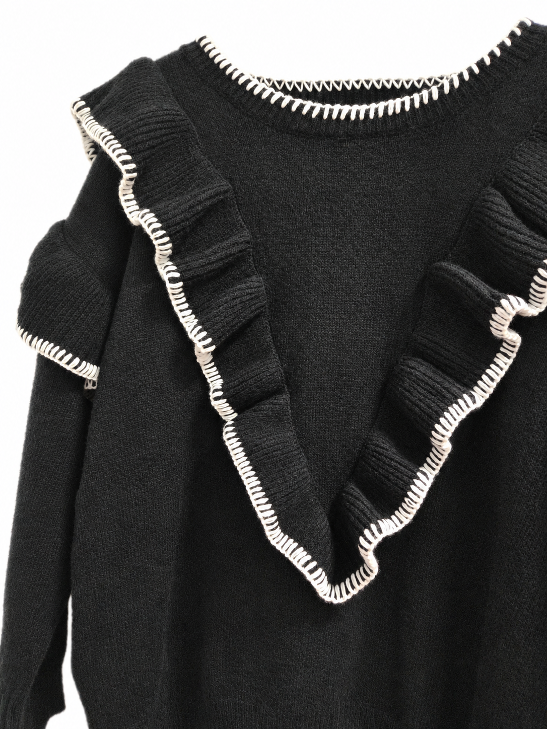 Détail des volants et des surpiqûres blanches du pull noir