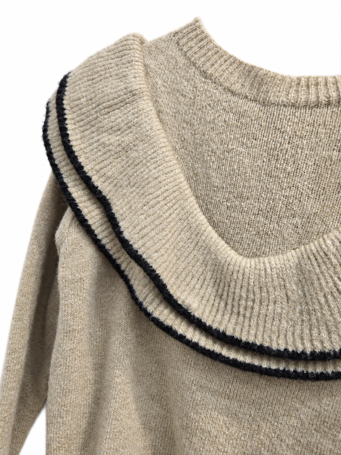 Détail du double volant liseré noir du pull beige